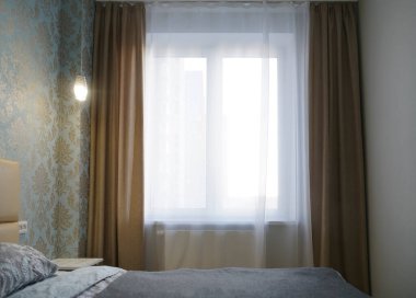 Parlak ve rahat modern yatak odası, soyunma odası, geniş pencere ve geniş pencere pervazı komodinli ve yumuşak yastıklı okumak için..