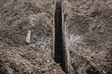 Kanalizasyon için hendek kazmak. Kablo döşemek için uzun bir çukur kazıldı.