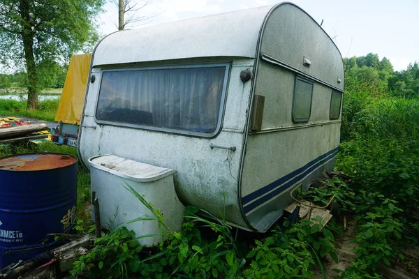 Vintage trailer near a summer like. Old, dirty abandoned trailer