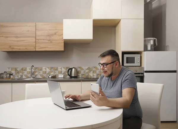 Hombre Caucásico Charlando Teléfono Móvil Cocina Trabajando Portátil Interior Cocina — Foto de Stock