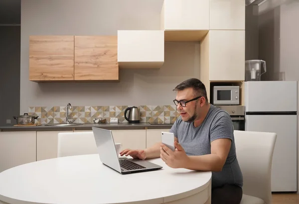 Hombre Caucásico Charlando Teléfono Móvil Cocina Trabajando Portátil Interior Cocina — Foto de Stock