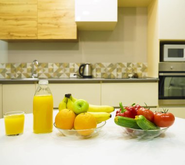 Modern stil mutfak içinde sebzeler ve beyaz ahşap masada meyveler. Parlak beyaz mutfak ve ev eşyaları. Sağlıklı yaşam tarzı kavramı. Yiyecek ve içecek..