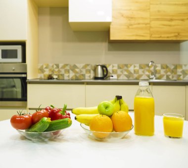 Modern stil mutfak içinde sebzeler ve beyaz ahşap masada meyveler. Parlak beyaz mutfak ve ev eşyaları. Sağlıklı yaşam tarzı kavramı. Yiyecek ve içecek..