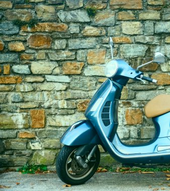 Güzel klasik tasarım gri renkli Vespa scooter, taştan duvar zeminine park etmiş bej koltuklu minder. SALZBURG, AUSTRIA