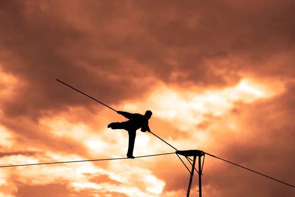 Wandering tightrope walker playing on  sky background. Silhouette of Equilibrist businessman with pole on the rope. idea concept of help and insurance, belay in business. Show in air