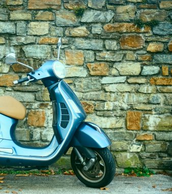 SALZBURG, AUSTRIA - 06 Aralık 2019: Taş duvar arka planında bej koltuk minderi olan güzel klasik tasarım gri Vespa scooter
