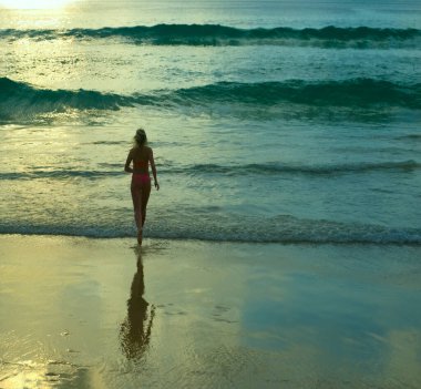 Arkadan bak. Okyanusa koşan kadın görüntüsü. Gün batımı. Deniz kıyısında koşan pembe mayo giymiş romantik bir kız. Güneşli sahil geçmişi. Dikiz aynası. büyük dalgalar.