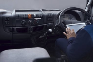 Adamın elinde tablet bilgisayar var. Kamyon ya da otobüs durağında seyrüsefer yapan tablet. Yüzü yok.