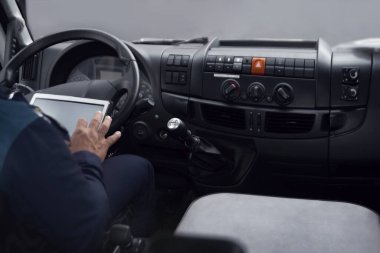 Adamın elinde tablet bilgisayar var. Kamyon ya da otobüs durağında seyrüsefer yapan tablet. Yüzü yok.