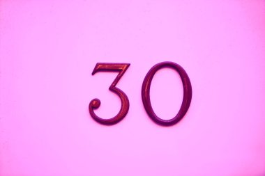 Pembe taş duvarda 30 numaralı mor demir. Metal rakam 30 (30).