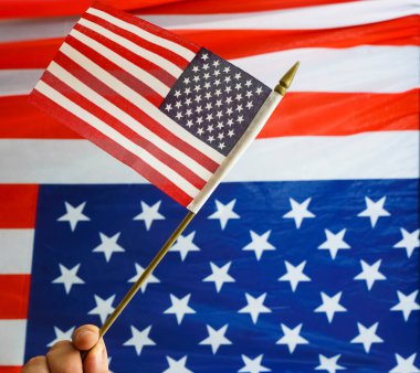 Amerikan bayrağına karşı elinde yıldızlar ve çizgiler olan küçük bir Amerikan bayrağı. 4 Temmuz. bağımsızlık günü. 
