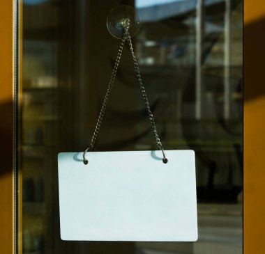 Kafenin cam kapısında asılı beyaz panoyu kapat. Bulanık arkaplan. 