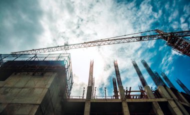 İnşaat alanında vinç ve takviye kuvvet. Yüksek binaların arka planında inşaat elementleri