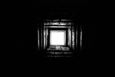 Tünelin sonunda, ucu tünelden parlayan bir ışık olan kare beton drenaj tüneli. Boş kare beton tünel. Kuru, terk edilmiş askeri sığınak. Tünelin sonunda bir ışık.