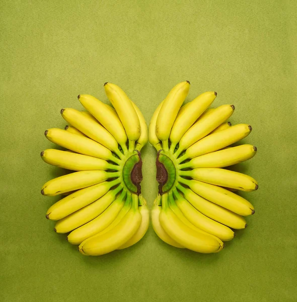 two Bunches of yellow small bananas isolated on green background. empty copy space for inscription.