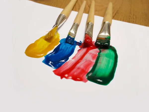 Colorful paint strokes with paint cans on white sheet of paper on wooden table background