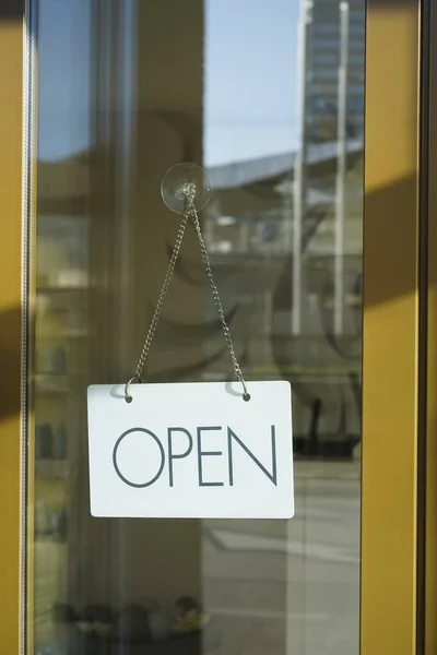 Close up of white  open sign hanging on glass door of cafe. Blurry background. Opened concept.