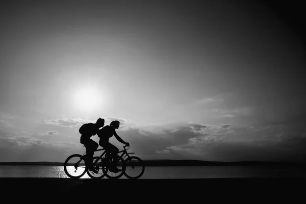 空虚な空間 日没の自転車でスポーティ友達 海岸沿いを自転車で走っています 自然を背景にスポーツ — ストック写真