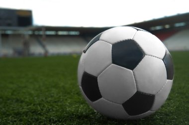 Yeşil çimlerde ve stadyum arka planında beyaz ve siyah futbol topu. Spor bahisleri