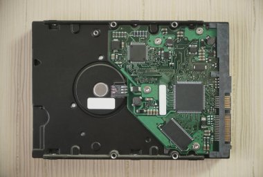 Bilgisayar HD - Sabit disk HDD sürücüsü, devre kartında SSD. Yakın plan. Ahşap masa arkasında izole edilmiş. en üstteki görünüm.