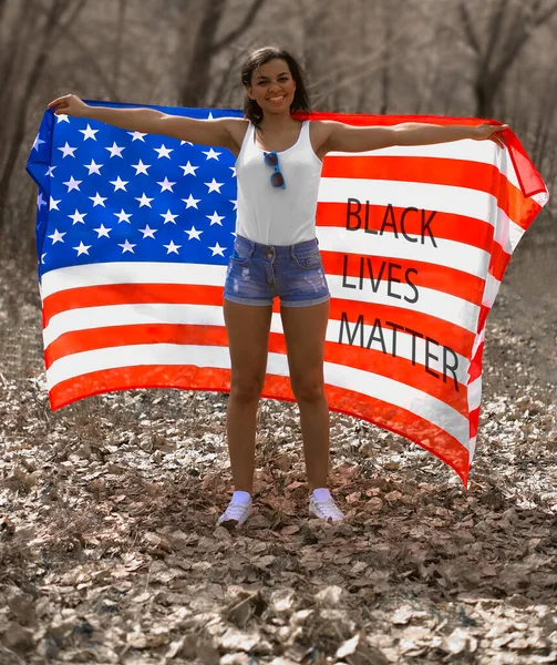 アフリカ系アメリカ人の女性がアメリカ国旗を手に立っている Black Lives Matter Blmのアイデア 春の季節だ 去年の葉 笑顔だ 7月4日 アメリカ独立記念日 — ストック写真