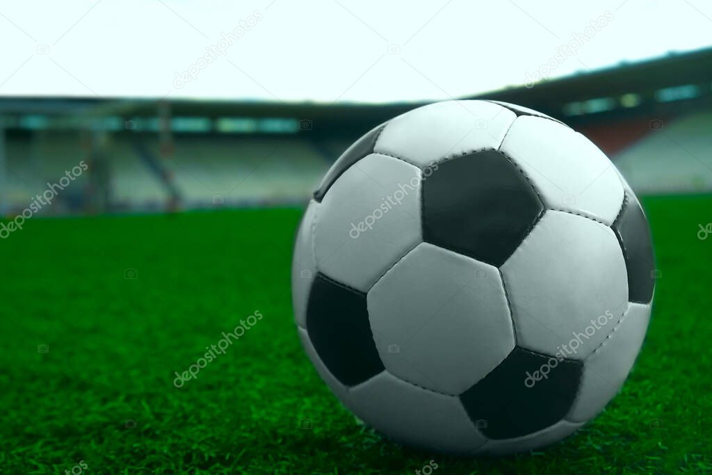 white and black soccer ball on green grass and stadium background. sports betting idea