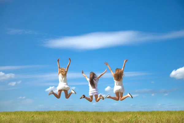 Rug Achteraanzicht Van Threeyoung Vrouwen Springen Blauwe Lucht Achtergrond Zomerveld — Stockfoto