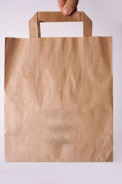 Kahverengi Işi Kağıt Çanta Beyaz Arka Planda Erkek Eliyle Izole — Stok fotoğraf