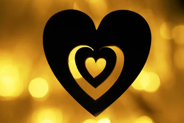 silhouette of black heart  on yellow golden background. garland  lighting bokeh at night. backdrop wallpaper. blurred  backdrop. happy Valentines day. 14th february.