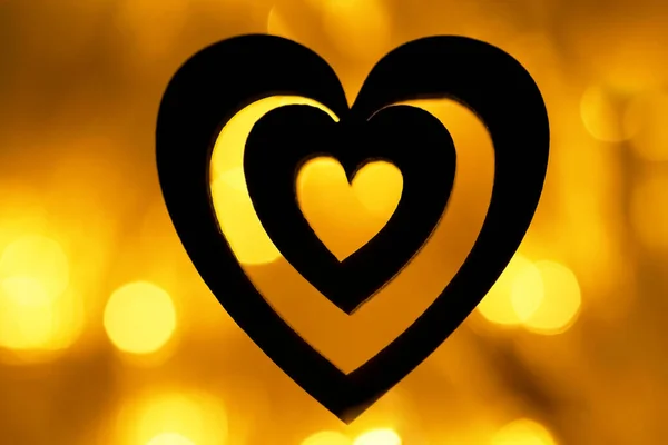 黄金の背景に黒いハートのシルエット 夜はガーランド照明のボケ 壁紙の背景 背景がぼやけてる ハッピーバレンタインデー 2月14日 — ストック写真