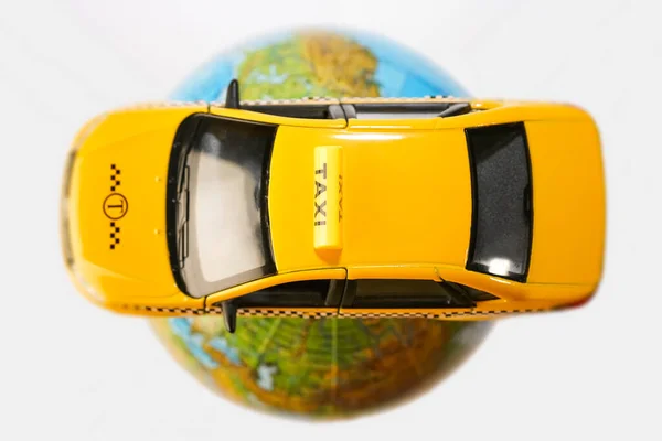 黄色のタクシーカーの屋根の上の地球 白い背景に隔離されたプラスチック製のおもちゃモデル 碑文のための空のコピースペース — ストック写真