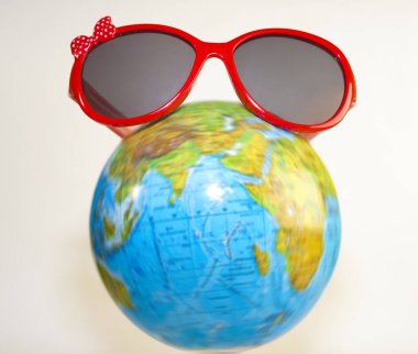 Kırmızı güneş gözlükleri dünyanın üzerinde duruyor. Beyaz arka planda izole edilmiş. Turizm, ekoloji, tatil ve küreselcilik kavramı. 