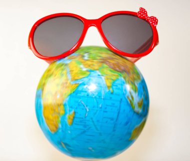 Kırmızı güneş gözlükleri dünyanın üzerinde duruyor. Beyaz arka planda izole edilmiş. Turizm, ekoloji, tatil ve küreselcilik kavramı. 