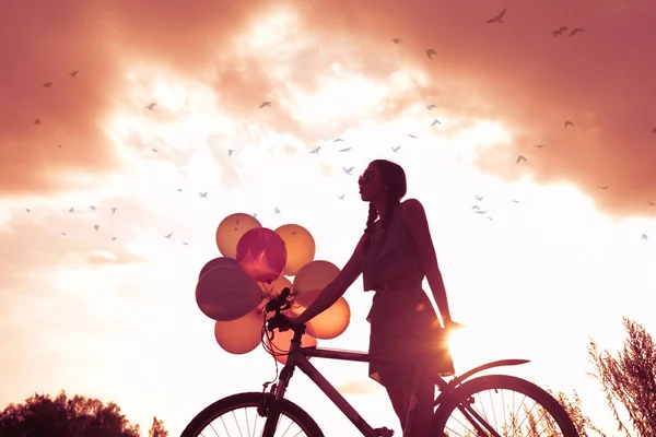 穿着性感连衣裙骑自行车飞气球的小女孩 — 图库照片