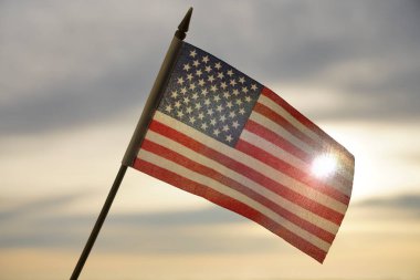Yakın plan Amerikan bayrağı arkadan gelen güneş ışığıyla gökyüzünde dalgalanıyor. Amerika Birleşik Devletleri bayrağı - geri aydınlandı. 4 Temmuz - Bağımsızlık Günü