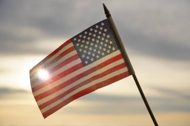 Yakın plan Amerikan bayrağı arkadan gelen güneş ışığıyla gökyüzünde dalgalanıyor. Amerika Birleşik Devletleri bayrağı - geri aydınlandı. 4 Temmuz - Bağımsızlık Günü