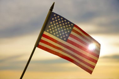 Yakın plan Amerikan bayrağı arkadan gelen güneş ışığıyla gökyüzünde dalgalanıyor. Amerika Birleşik Devletleri bayrağı - geri aydınlandı. 4 Temmuz - Bağımsızlık Günü