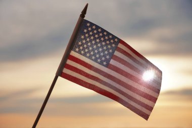 Yakın plan Amerikan bayrağı arkadan gelen güneş ışığıyla gökyüzünde dalgalanıyor. Amerika Birleşik Devletleri bayrağı - geri aydınlandı. 4 Temmuz - Bağımsızlık Günü