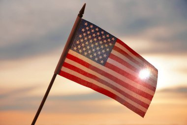 Yakın plan Amerikan bayrağı arkadan gelen güneş ışığıyla gökyüzünde dalgalanıyor. Amerika Birleşik Devletleri bayrağı - geri aydınlandı. 4 Temmuz - Bağımsızlık Günü