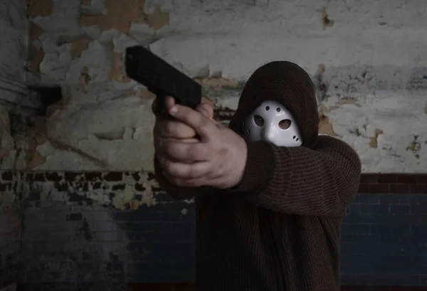 头戴头罩的强盗 枪托在旧瓷砖墙的背景上 男人戴着白色冰球面罩和保暖套头衫 — 图库照片