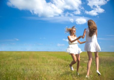 Güzel kızlar yaz tarlasında bulutlarla mavi gökyüzünde dans ediyor.. 