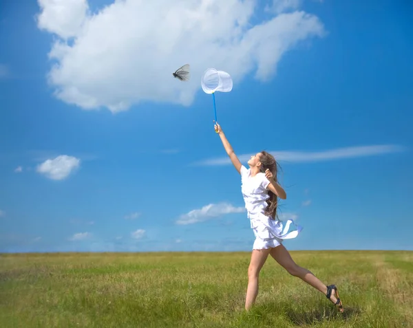 girl with a ring-net on a summer filed. Sunny day. smiling girl holds butterfly net on blue sky with clouds. young adult  woman catching a butterfly in scoop-net. Female with long hair.