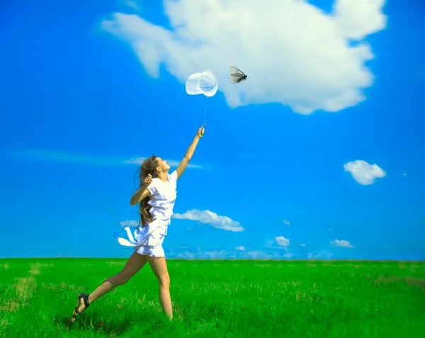 girl with a ring-net on a summer filed. Sunny day. smiling girl holds butterfly net on blue sky with clouds. young adult  woman catching a butterfly in scoop-net. Female with long hair.