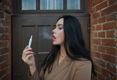 Sigara içen sigara içen kadın gerçek tütünsüz sigara doldurma cihazı kullanıyor. Analog ve elektronik sigaralar arasında melez bir teknoloji..