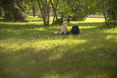  no faces. young couple in a park  on fresh green grass. spring time season. woman smoking cigarette near man. 