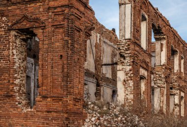 Penceresi kırık ve çatısı olmayan terk edilmiş bir bina. Tarladaki eski kırmızı tuğlalı ev. Gökyüzü zemininde birçok boş penceresi olan eski yıkılmış tuğla bina.