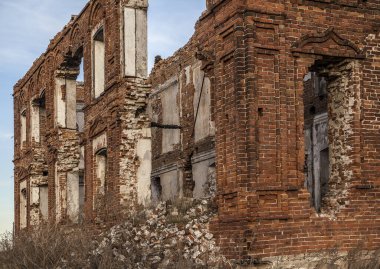 Penceresi kırık ve çatısı olmayan terk edilmiş bir bina. Tarladaki eski kırmızı tuğlalı ev. Gökyüzü zemininde birçok boş penceresi olan eski yıkılmış tuğla bina.