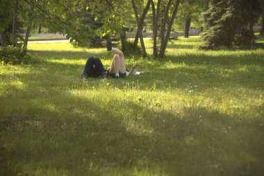  no faces. young couple in a park  on fresh green grass. spring time season. woman smoking cigarette near man. 