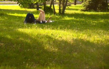  no faces. young couple in a park  on fresh green grass. spring time season. woman smoking cigarette near man. 
