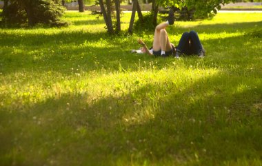  no faces. young couple in a park  on fresh green grass. spring time season. woman smoking cigarette near man. 